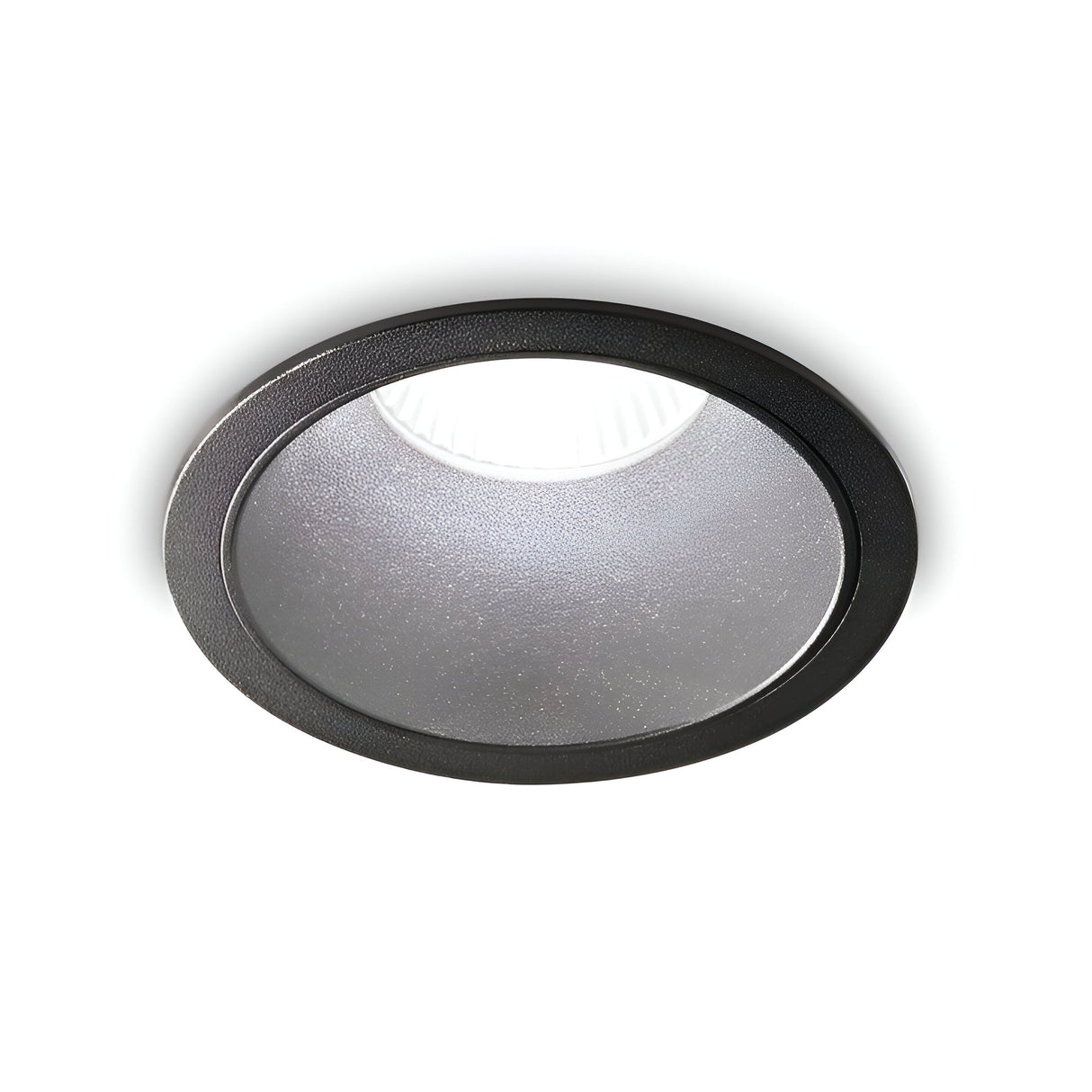 A close-up view of the Sally LED Round Recessed Trim Downlight in black, shining against a white background. This IP65-rated fixture features a textured glass covering that evenly disperses its warm 3000K light.