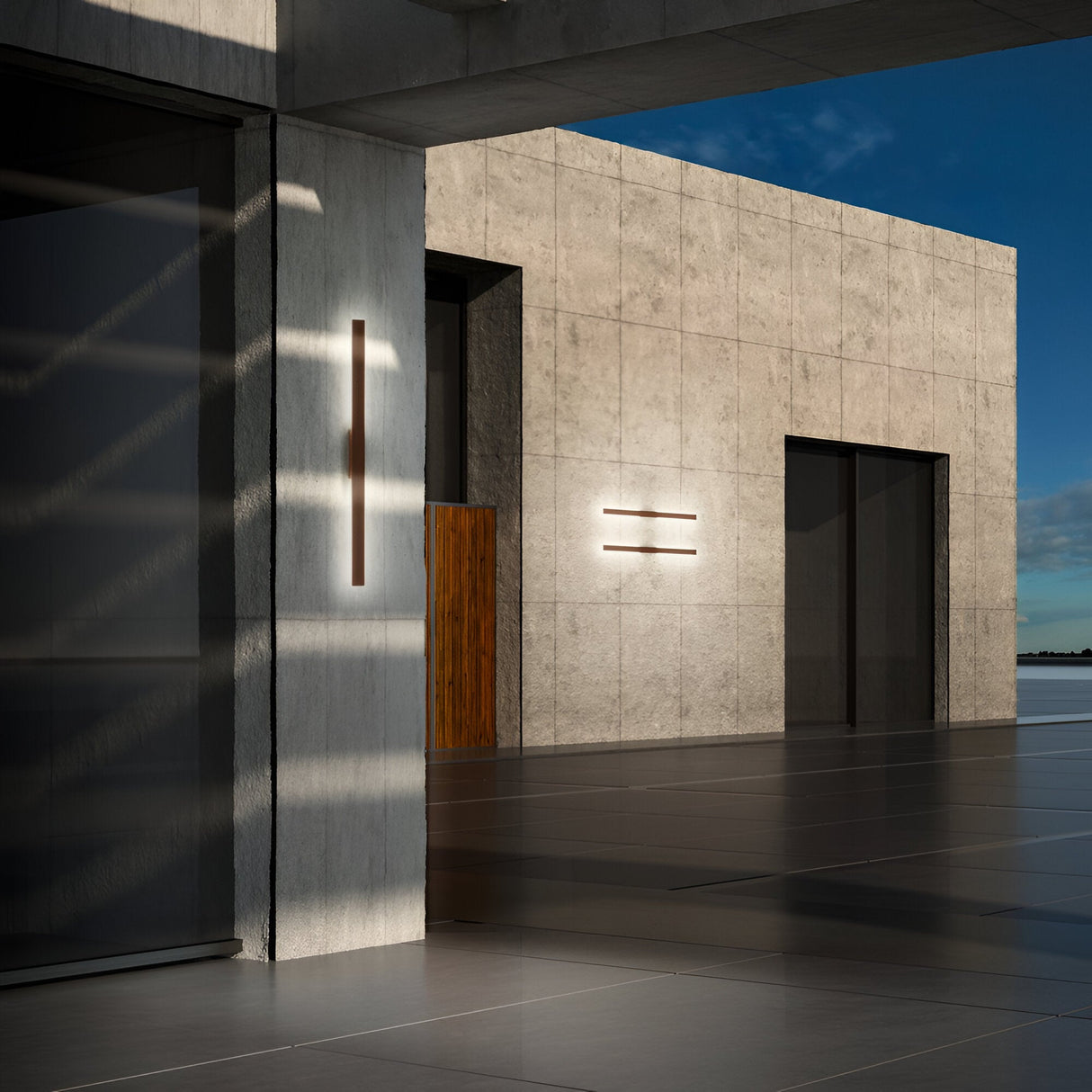 In the modern architectural landscape, a minimalist concrete facade is accentuated by a wooden door and the sleek design of the Reflek Outdoor LED Linear Wall Light in brown. Overlooking a calm body of water, this elegant 144cm light fixture with its energy-efficient 20W and warm 3000K illumination enhances the exterior's reflection of the clear sky, conveying an aura of tranquility and sophistication.
