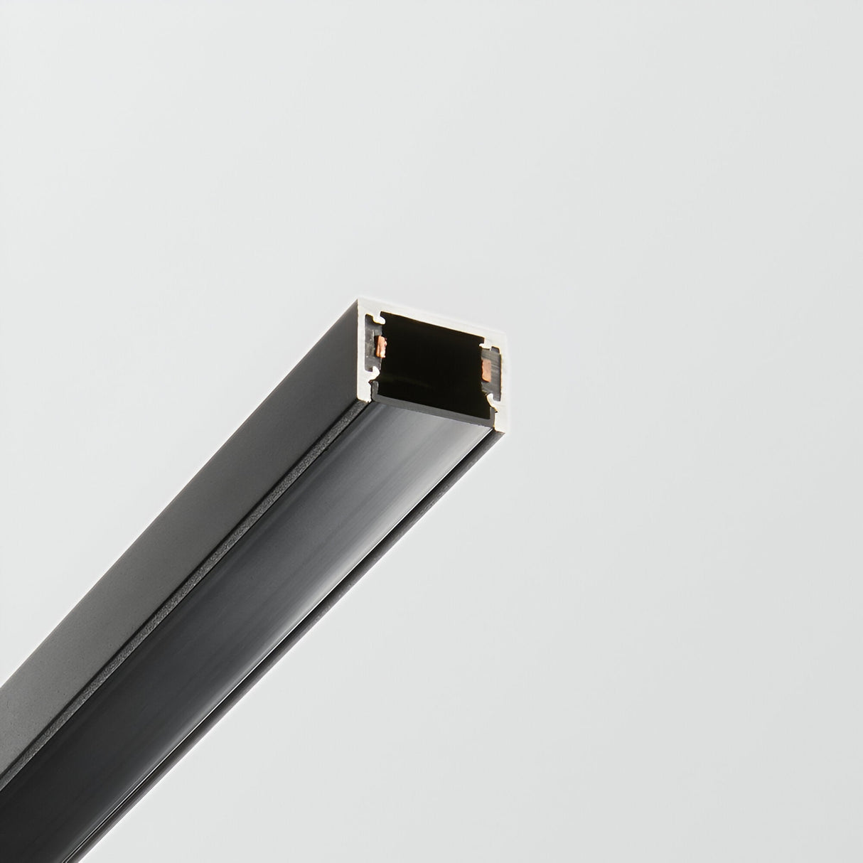 Close-up of the Viora Track Cover - Black, 1m against a plain white background. The track cover, with its sophisticated matte black finish, is open at the end, revealing its hollow interior and a few small connectors.