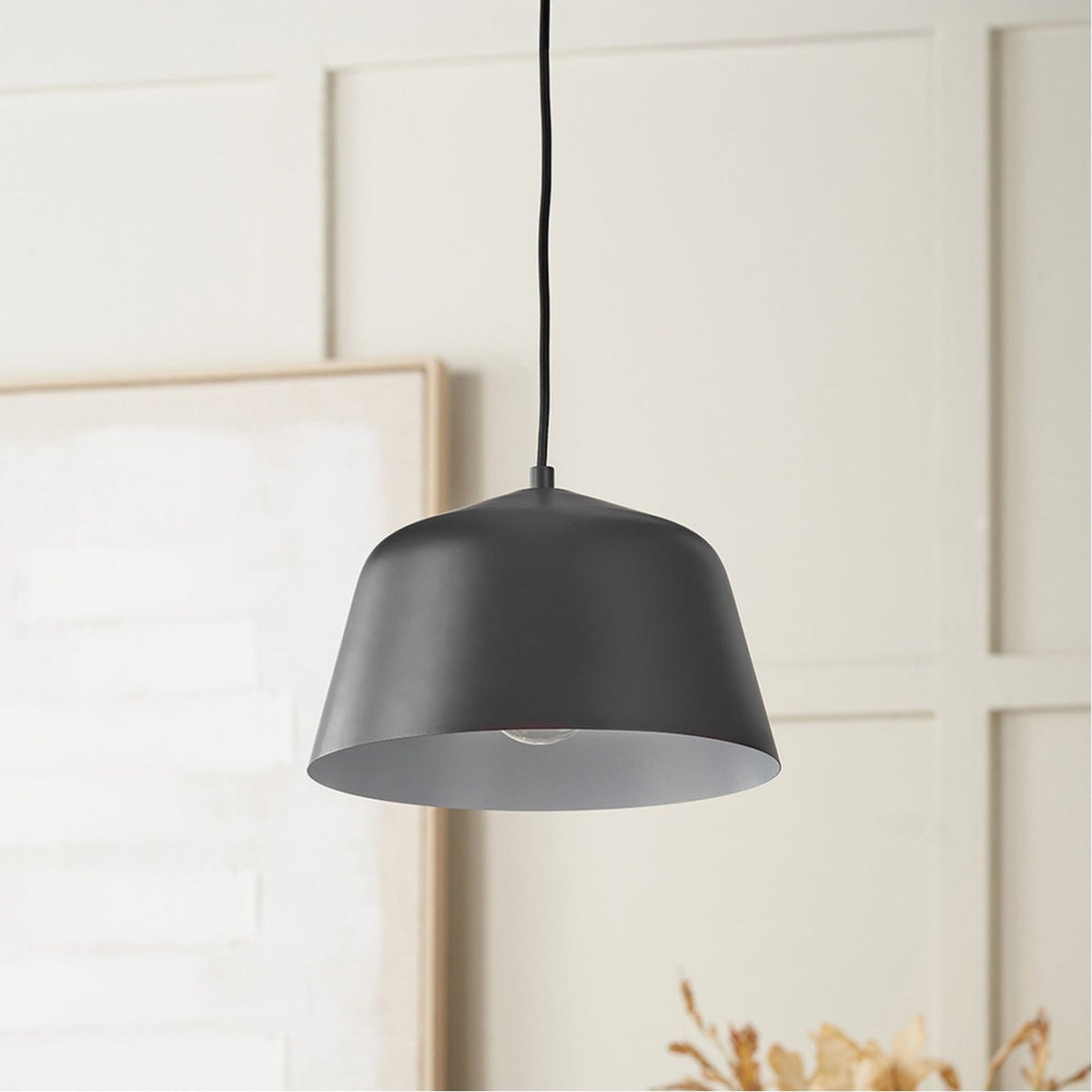 Amalie Black Metal Retro Pendant Light - 30cm, a tapered black steel dome shade on a black cord, hung in a room with panelled walls and a framed artwork.