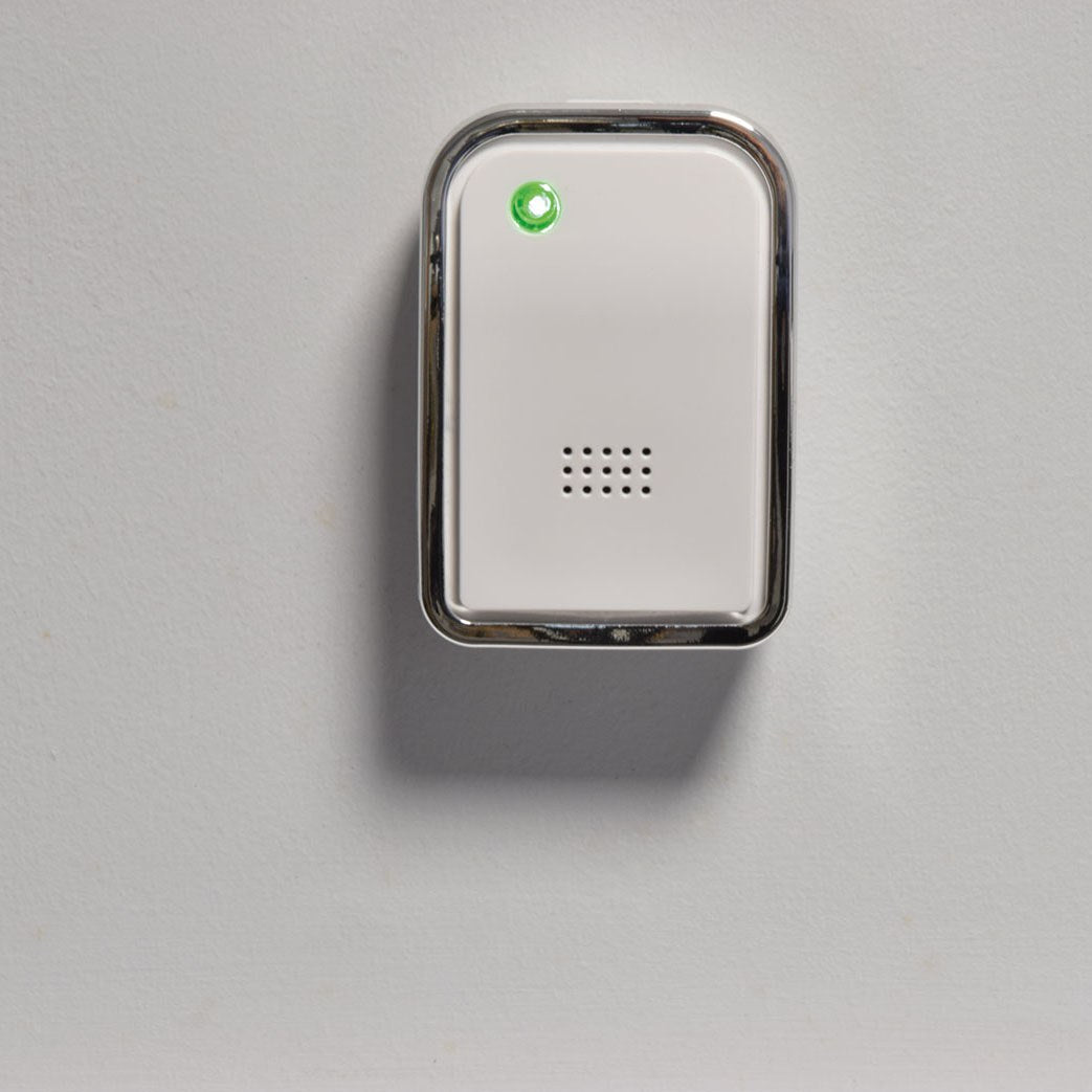 AVSL Mercury wireless door chime receiver wall-mounted on a light background, white casing with chrome trim, speaker grille and illuminated green LED indicator.