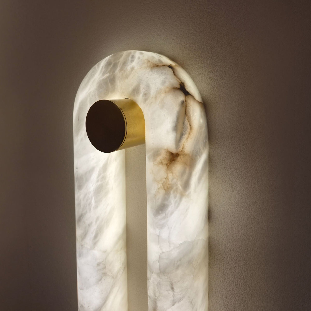 Serava LED Alabaster Wall Light Large in soft white, close-up of the arched stone body with brass cylindrical bracket, showing natural veining and warm integrated LED glow against a plain wall.