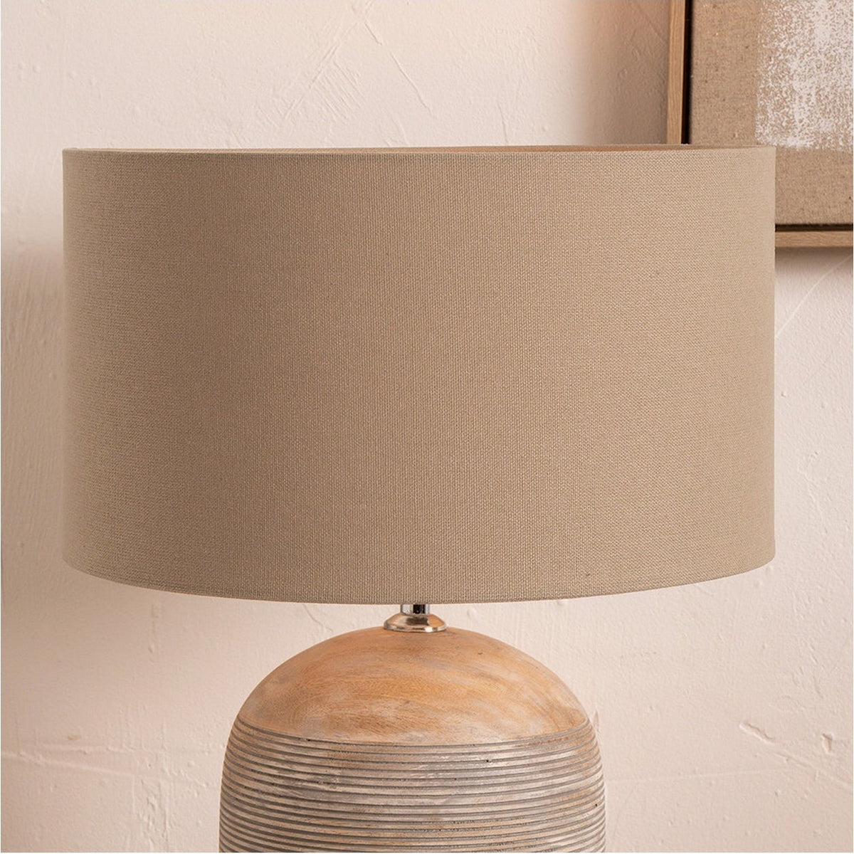Henry Taupe Handloom Cylinder Lampshade, 35cm, fabric drum shade on a round wooden lamp base, shown against a light wall with a framed picture.