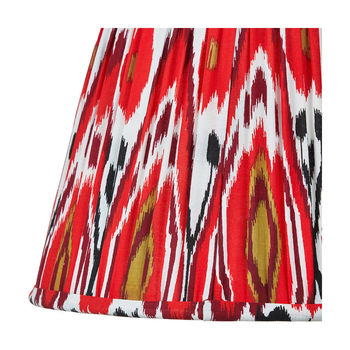 Close-up of the Izara Red Ikat Pleated Tapered Lampshade, 30cm, showing red, white and black ikat-patterned fabric with fine pleating and a folded trim edge.