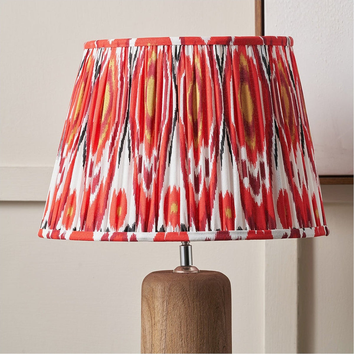 Izara Red Ikat Pleated Tapered Lampshade, 45cm, in red and white ikat-patterned fabric with pleated finish, shown on a wooden table lamp base.
