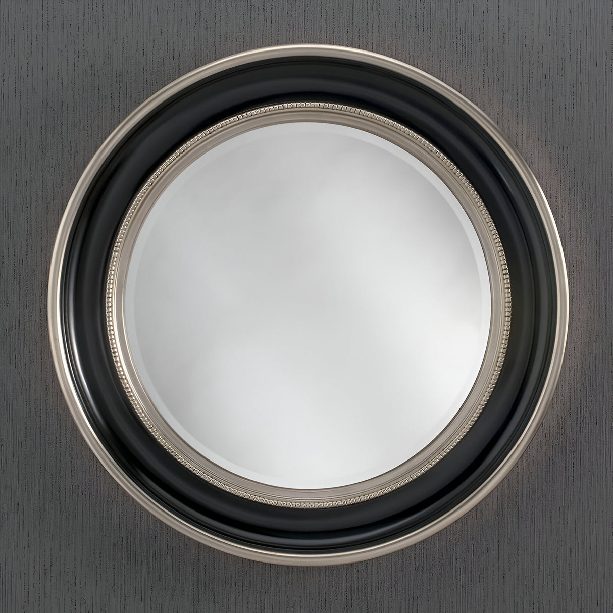 The Luxe Circle Wall Mirror Black/Silver - 91cm is elegantly mounted on a textured grey wall. Its smooth, clear surface captures light beautifully, combining modern design with timeless sophistication.