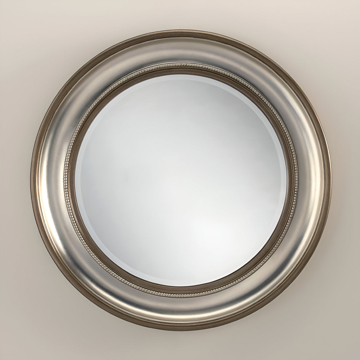 The Luxe Circle Wall Mirror Bronze/Silver - 91cm features a wide, decorative frame enhanced by intricate beading along the inner edge. Mounted on a light-colored wall, it adds an elegant touch to your home decor.