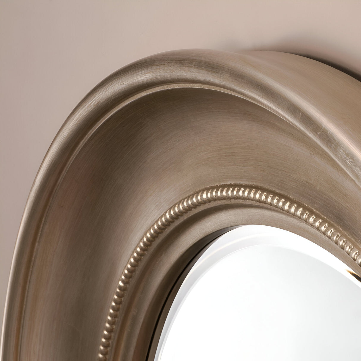 A close-up of the Luxe Circle Wall Mirror Silver - 91cm showcases its metallic frame featuring an elegant beaded design, ideal for multiple interior styles. The silver frame stands out beautifully against the neutral-colored wall, adding a touch of sophistication.