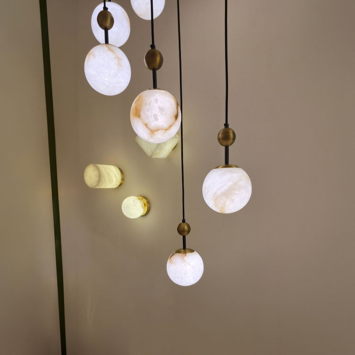 Lorixa 9-Light Cascading Alabaster Chandelier in brushed bronze, spherical globes at staggered drop heights, shown lit against a plain neutral wall.