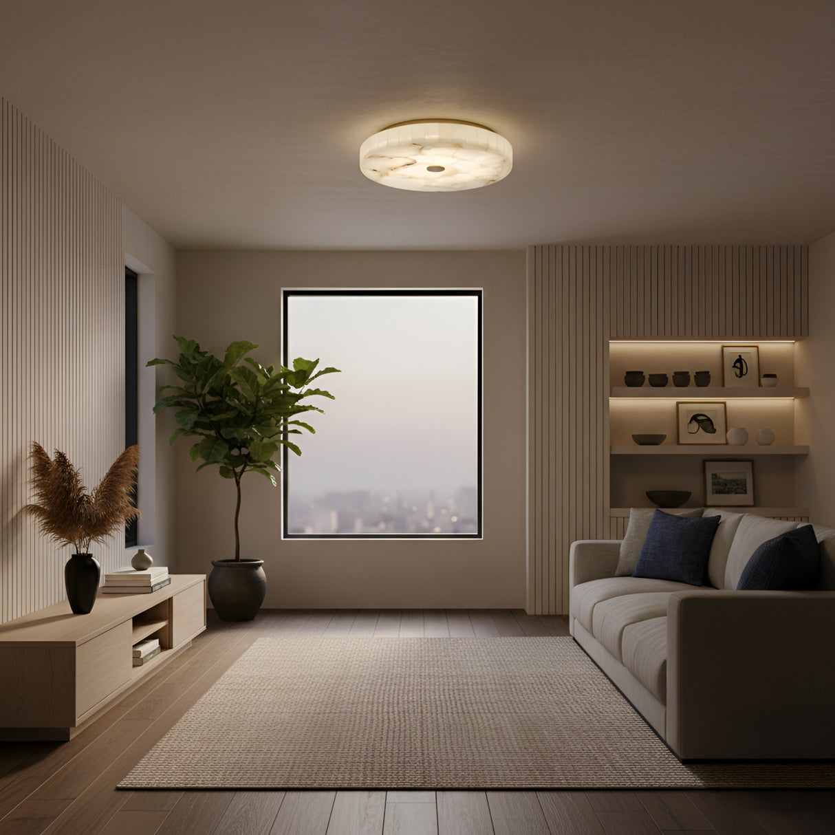 A modern living room features a beige sofa, neutral rug, potted plant, built-in shelves with decor, and a large window with a city view at dusk. The Veltrix LED Small Round Alabaster Flush Ceiling Light in brushed brass softly illuminates the space.