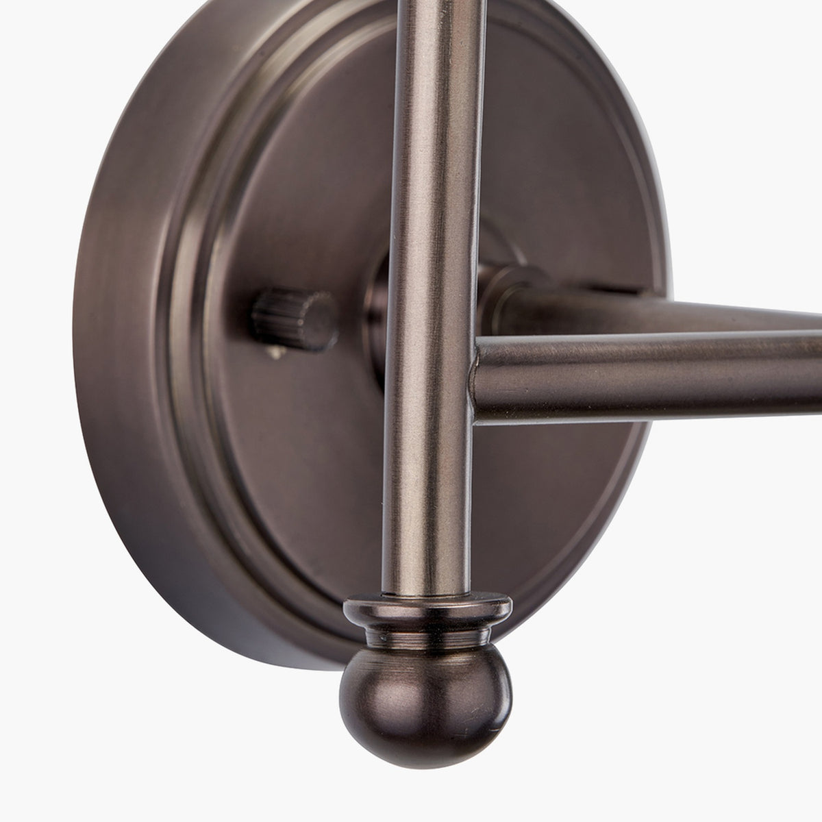 Close-up of the Piero Double Wall Light in antique bronze, showing the round metal backplate, dimmer knob, straight arm, and ball-tipped finial against a plain white background.