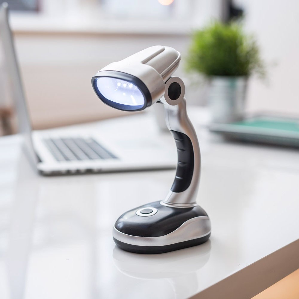 AVSL LYYT 12 LED USB desk lamp in silver and black with adjustable head and rubberised grip, shown on a white desk beside a laptop and potted plant.