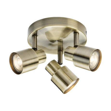 The Triple Spotlight - Antique Brass features three adjustable directional heads gracefully mounted on a round base, each GU10 spotlight artfully designed to cast light in various directions, enhancing both functionality and elegance.