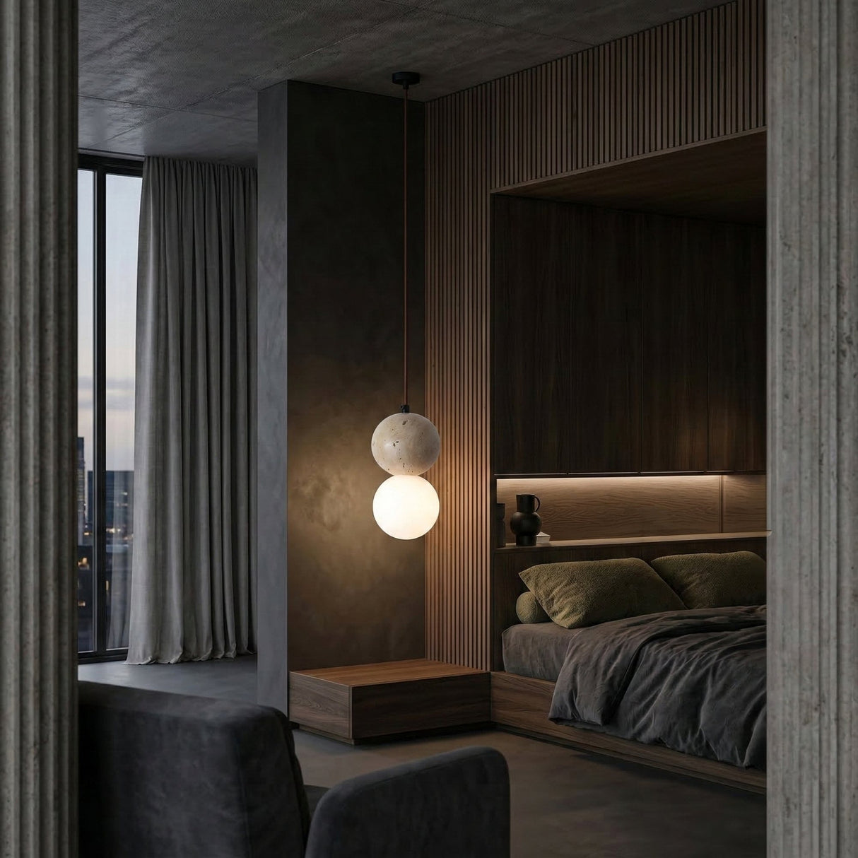 A modern, dimly lit bedroom with dark wood paneling, a large gray-bedded bed, and the Belvoro 1 Light Dual Sphere Travertine Single Pendant Light in light beige. Floor-to-ceiling curtains cover tall windows for a cozy, minimal vibe.