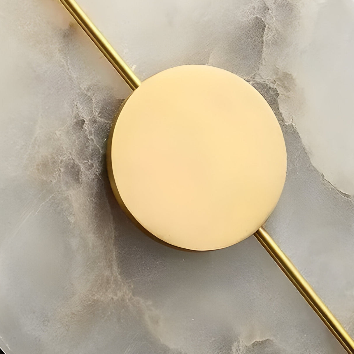 The Elaris LED Round Alabaster Wall Light in Soft White & Brass features a gold disc intersecting a slim rod on a marbled base, offering a modern, minimalist look—ideal as an accent or round wall light for contemporary interiors.