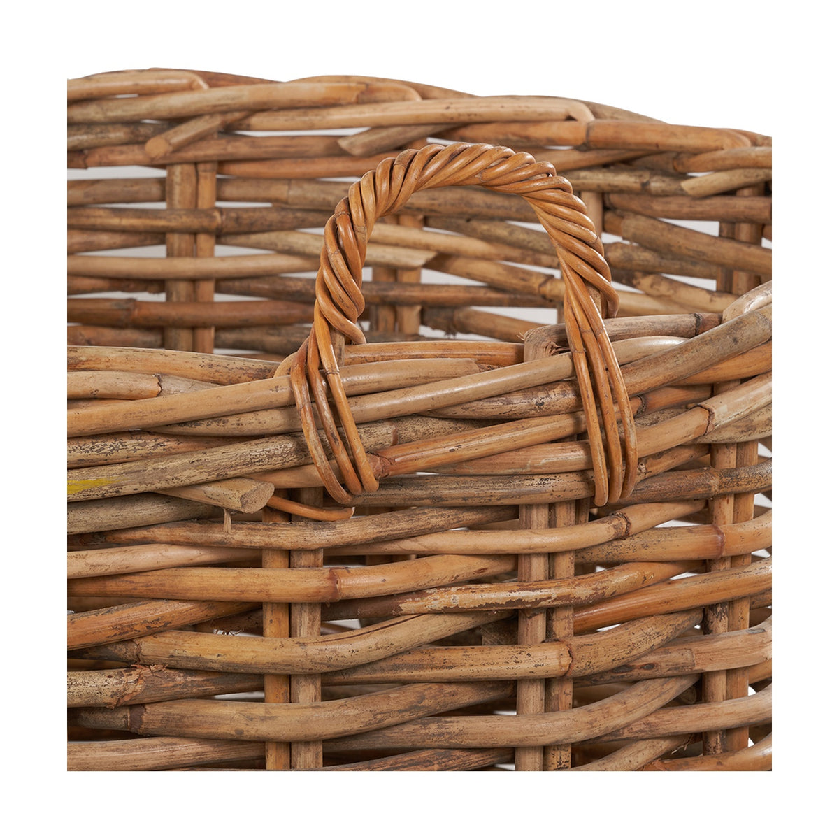 Close-up of the Tobs Chunky Rattan Log Basket in natural finish, showing woven rattan texture and a coiled rattan carry handle.