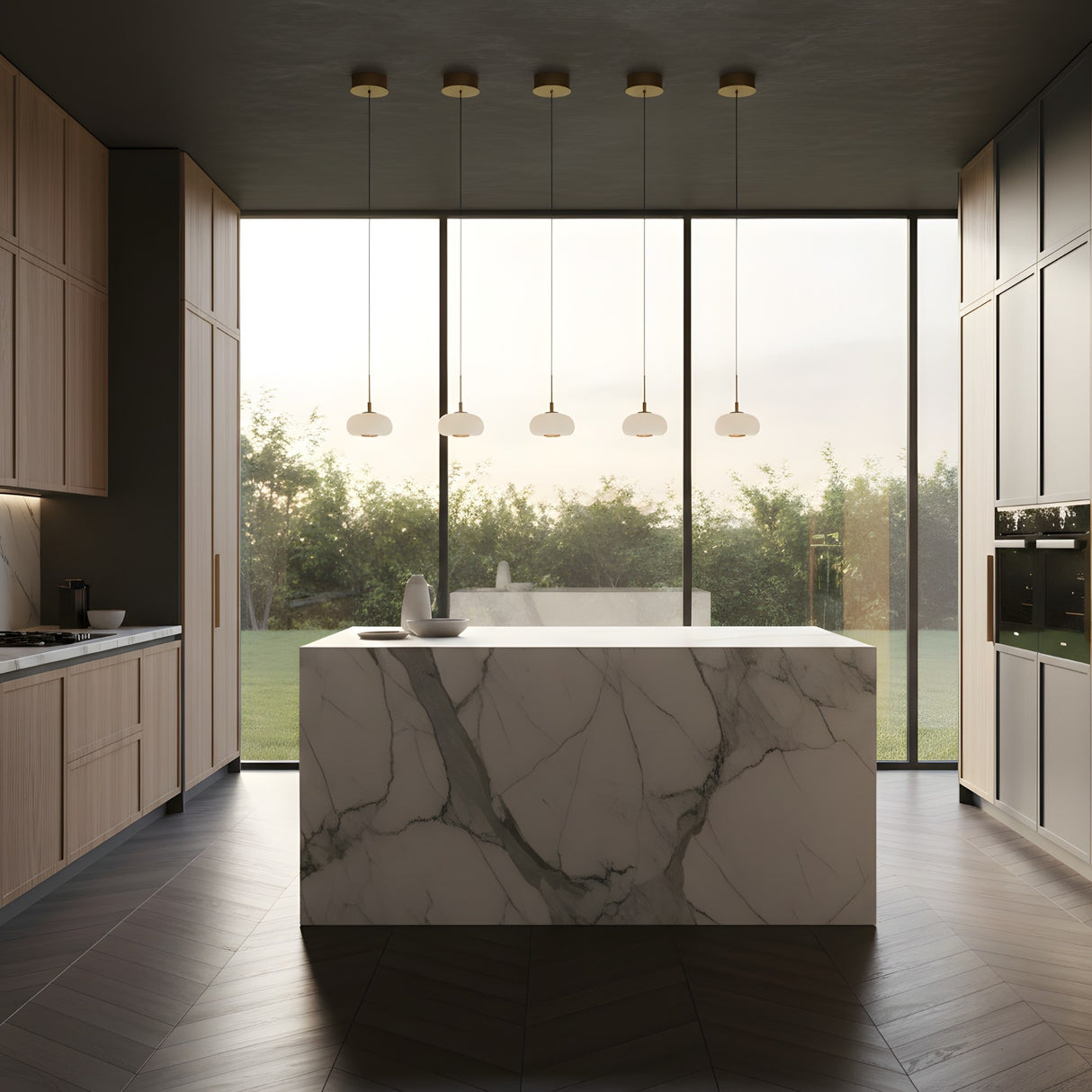 A modern kitchen with a large marble island, wood cabinets, built-in appliances, and floor-to-ceiling windows overlooking a green garden, illuminated by Aurevia LED Dome Alabaster Single Pendant Lights in brushed brass.