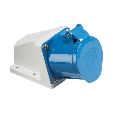 The 16A 2 Pole Earth Angled Surface Mount Socket in blue and white comes with an IP44 rating and a hinged cover for protection. Its mounted on a rectangular white base, secured by four metal screws, and designed to withstand various conditions.