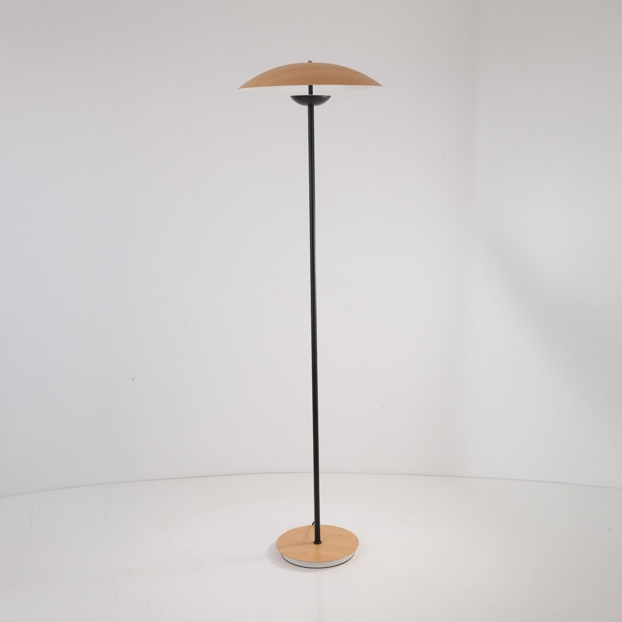 The Ex-Display Ginger LED Floor Lamp in black and oak features a slim black pole, round wooden base, and matching disc-shaped wooden shade, standing elegantly against a plain white background.
