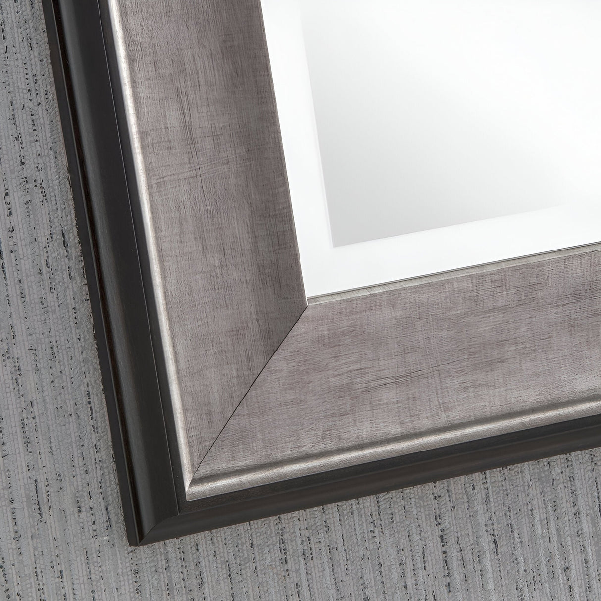 A detailed look at the Pulse Rectangle Wall Mirror - Grey showcases its understated elegance with a contemporary grey frame and beveled edge. The mirror's reflection highlights a light gray textured surface, accentuating its sleek design and adding a modern touch to any setting.