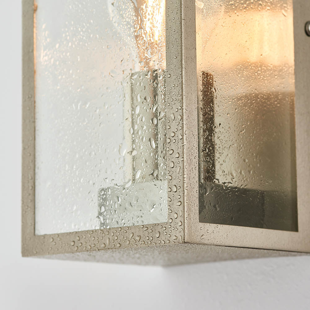 Close-up of Endon Castwick Lantern Wall Light in silver, showing the brushed steel box frame and water-speckled bevelled glass panels with a warm glow.