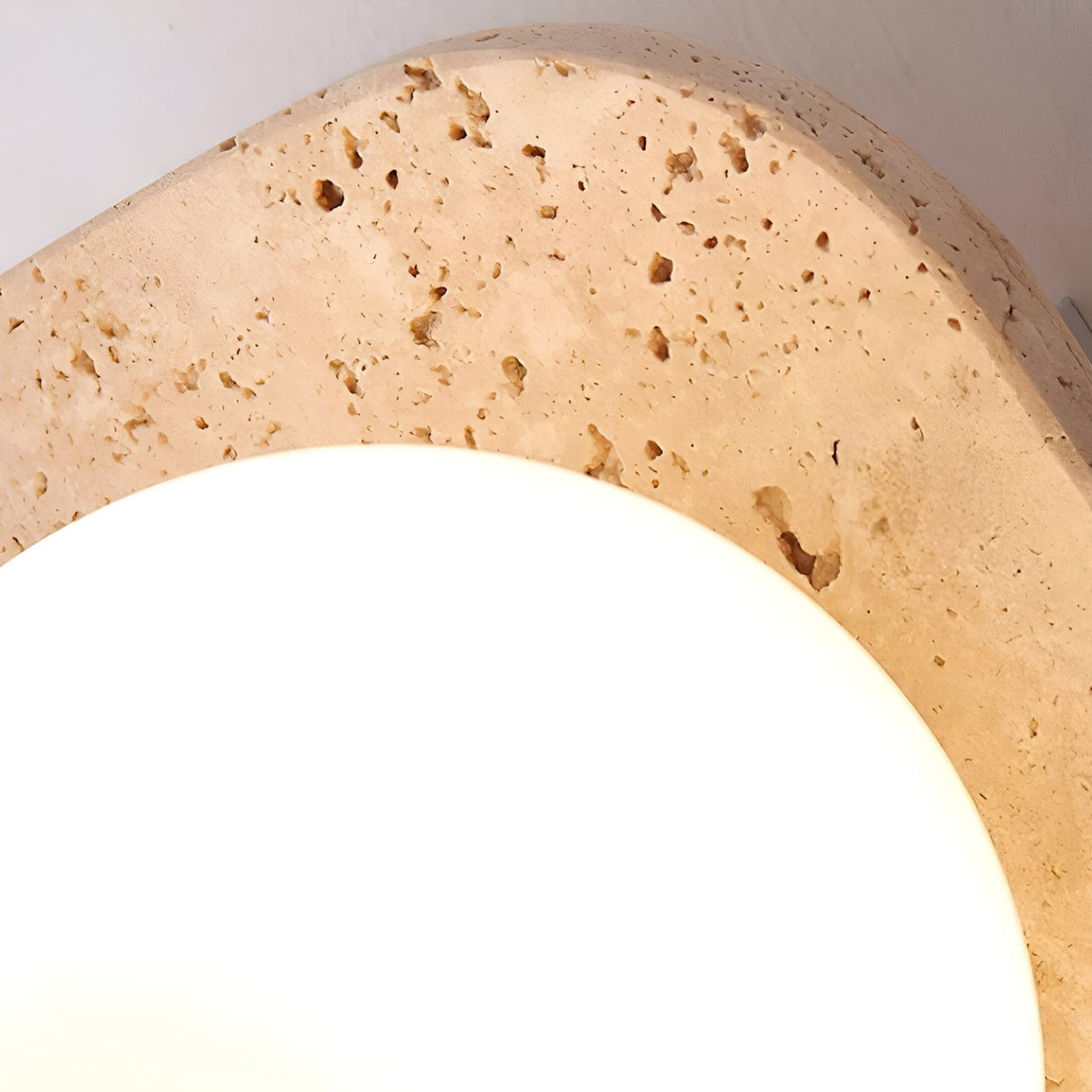 A close-up of the Virella 3 Light Vertical Travertine Wall Light in light beige, featuring a glowing white orb on a textured stone surface with natural patterns, adding layered ambient lighting to your space.