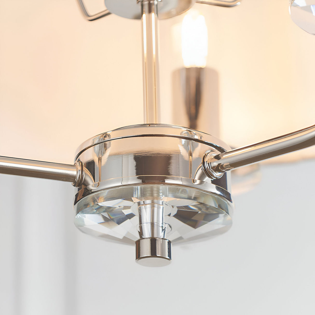 Close-up of the Endon Castdon 3 light pendant showing the polished nickel central hub, K9 crystal bobeche detail, and vintage white faux silk shade.