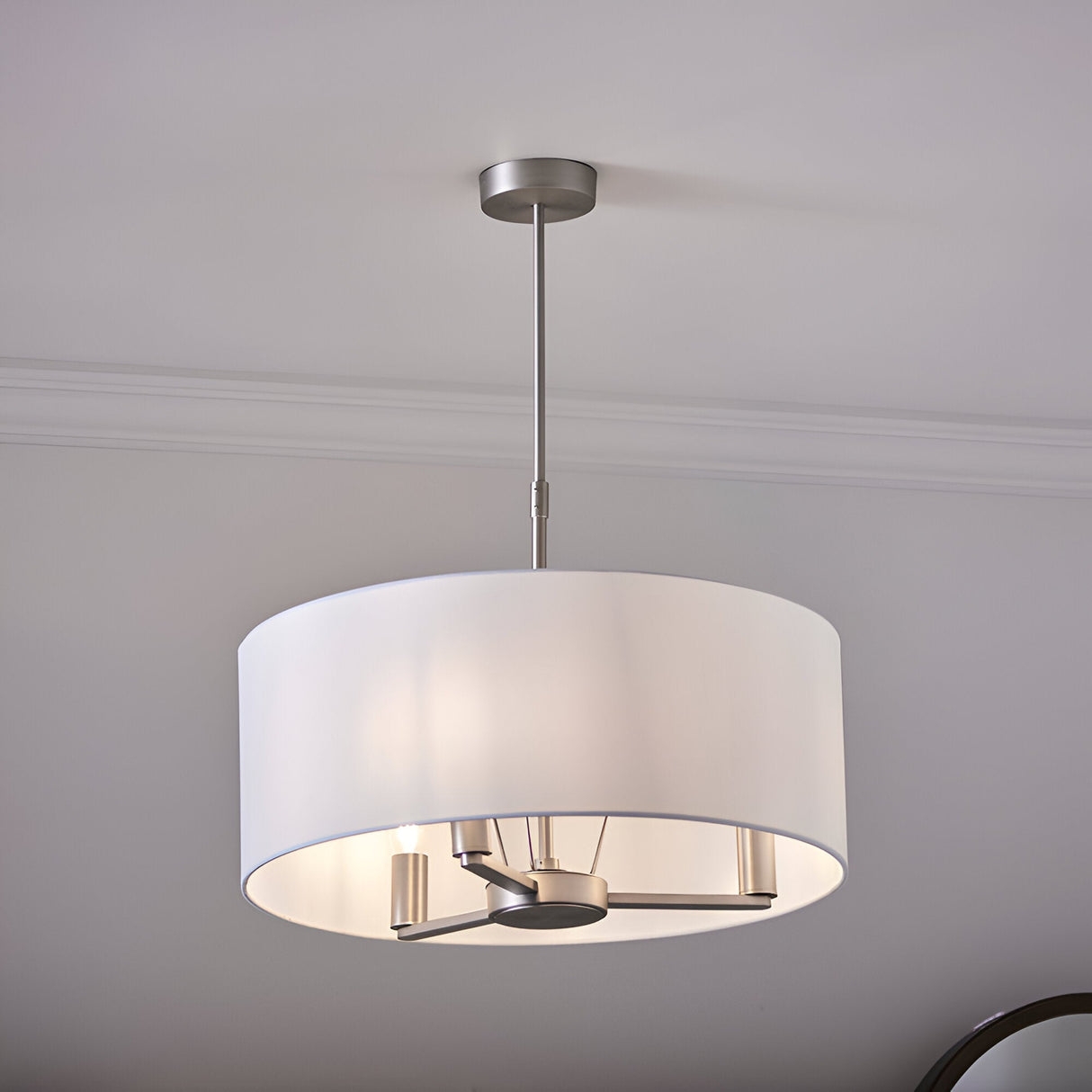 Endon Bexley large 3 light pendant in brushed nickel with a white faux silk drum shade, suspended from a ceiling in a soft grey room.