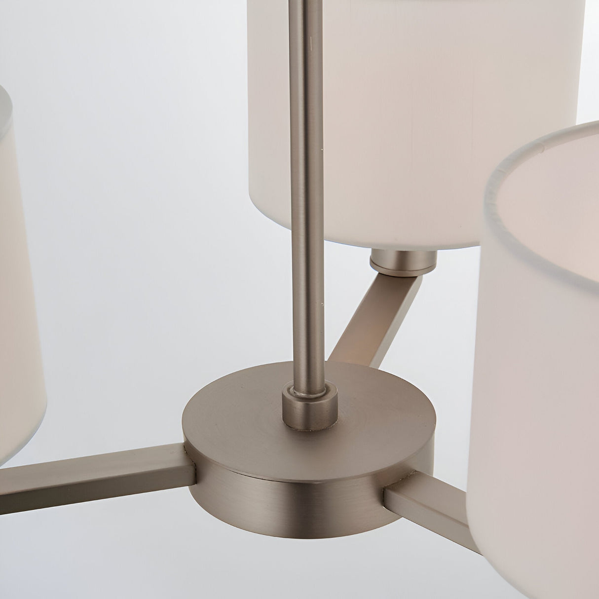 Close-up of the Bexley 3 Light Pendant's central matt nickel fitting, showing curved metal arms and white fabric shades on a plain white background.