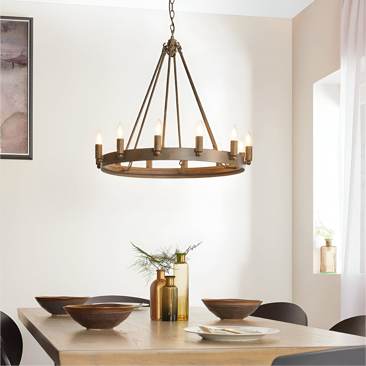 Bevgrove wagon-wheel pendant light in aged metal finish with candle-style bulbs, hung above a wooden dining table in a neutral-toned room.