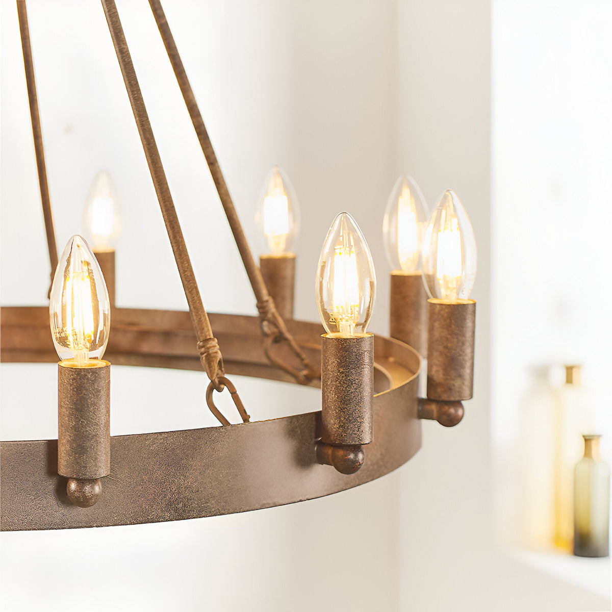 Bevgrove 12 Light Pendant in aged metal, close-up of the ring frame with candle-style bulbs lit, set against a plain light background.