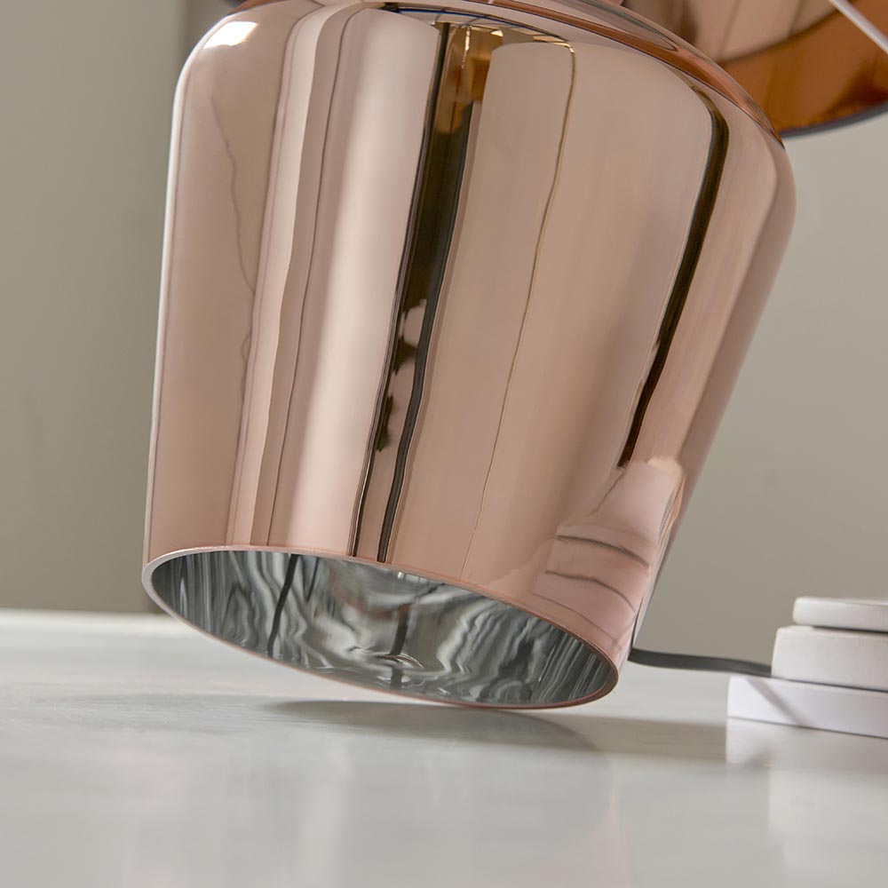 Close-up of the Endon Danefield table lamp's polished copper plated glass base tilted on a light surface, revealing its warm reflective inner.