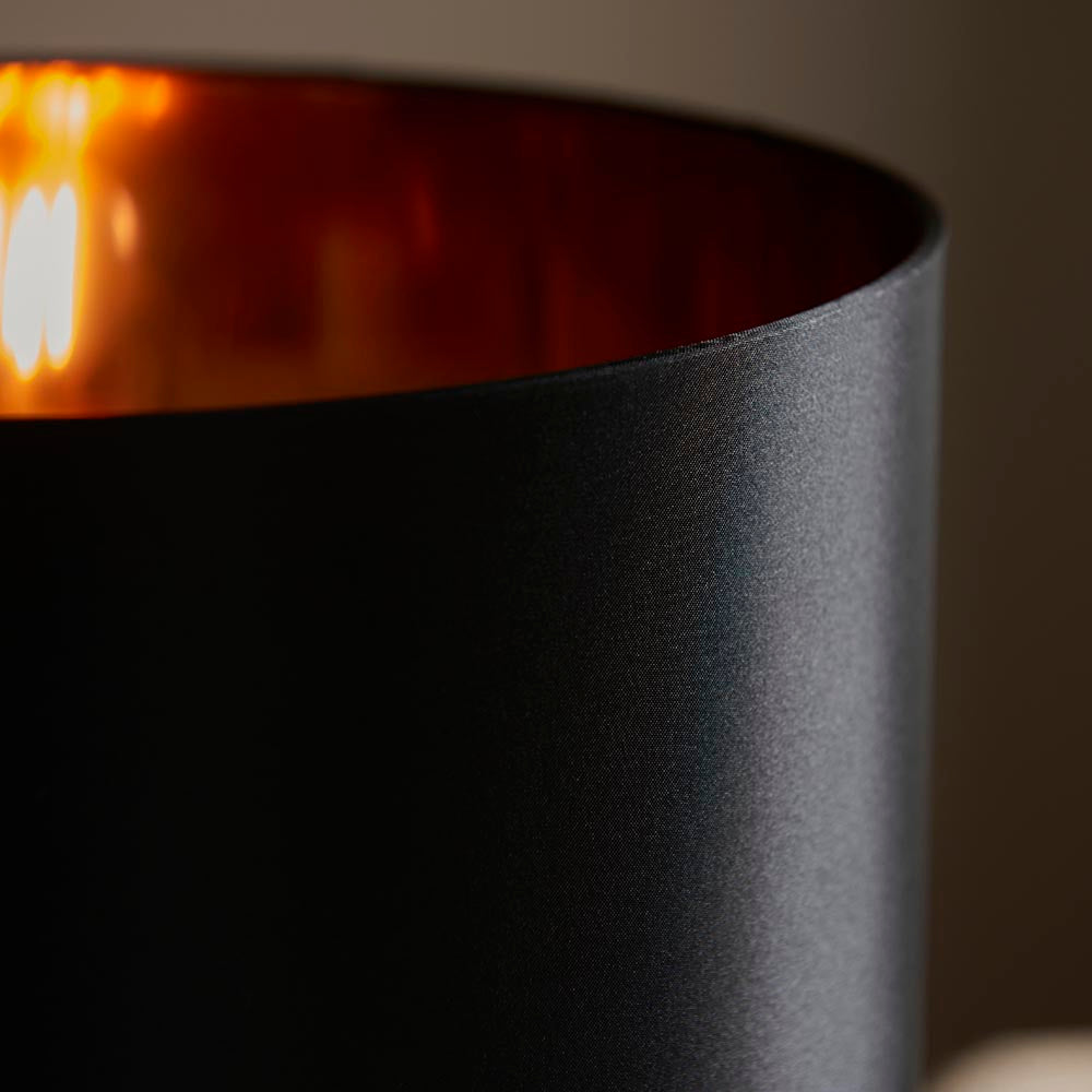 Close-up of the Endon Danefield table lamp's black fabric shade with a warm copper-effect reflective inner lit by a single E27 bulb.