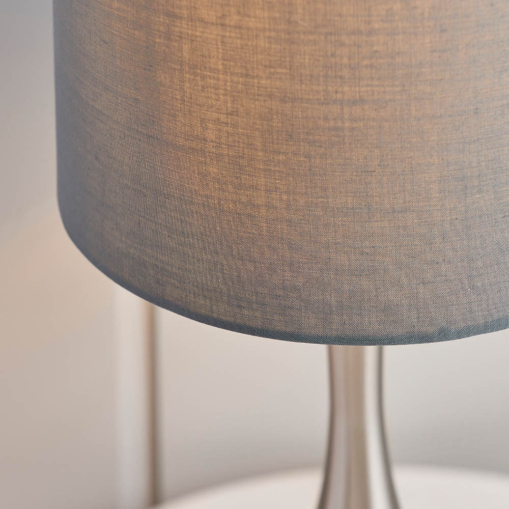 Close-up of the Endon Chartbury LED table lamp showing its grey fabric drum shade and slender satin nickel base against a pale background.