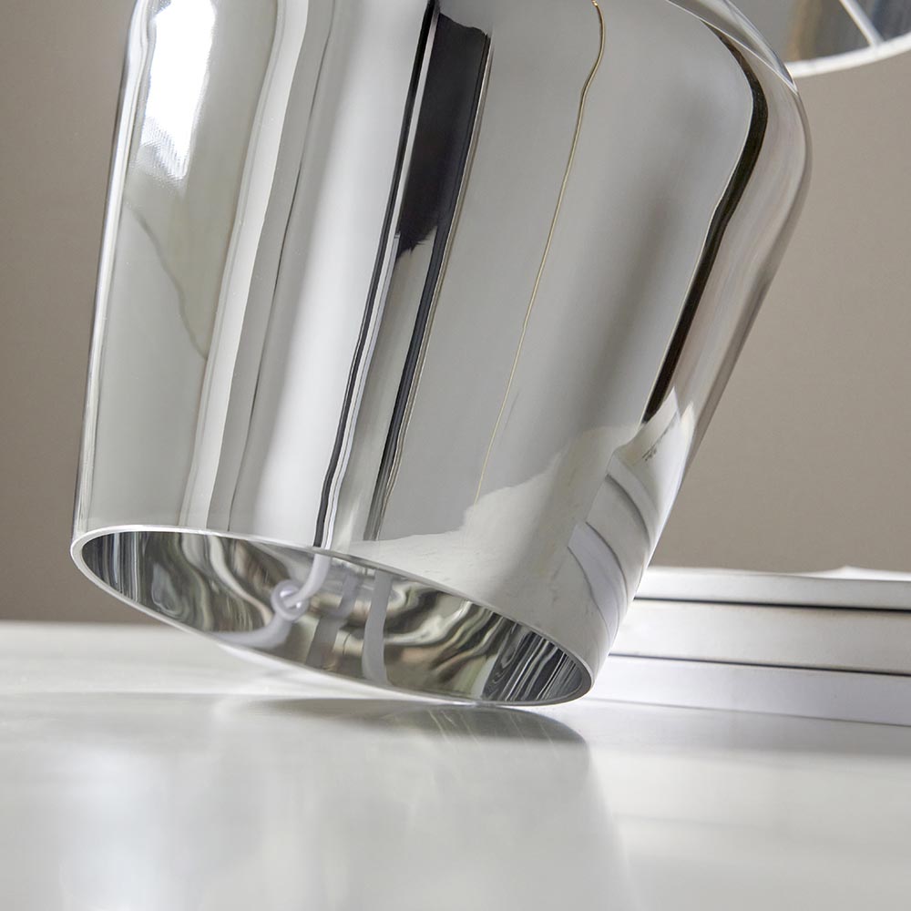Danefield Table Lamp in chrome, close-up of the mirrored glass base and cream fabric shade edge on a light surface.