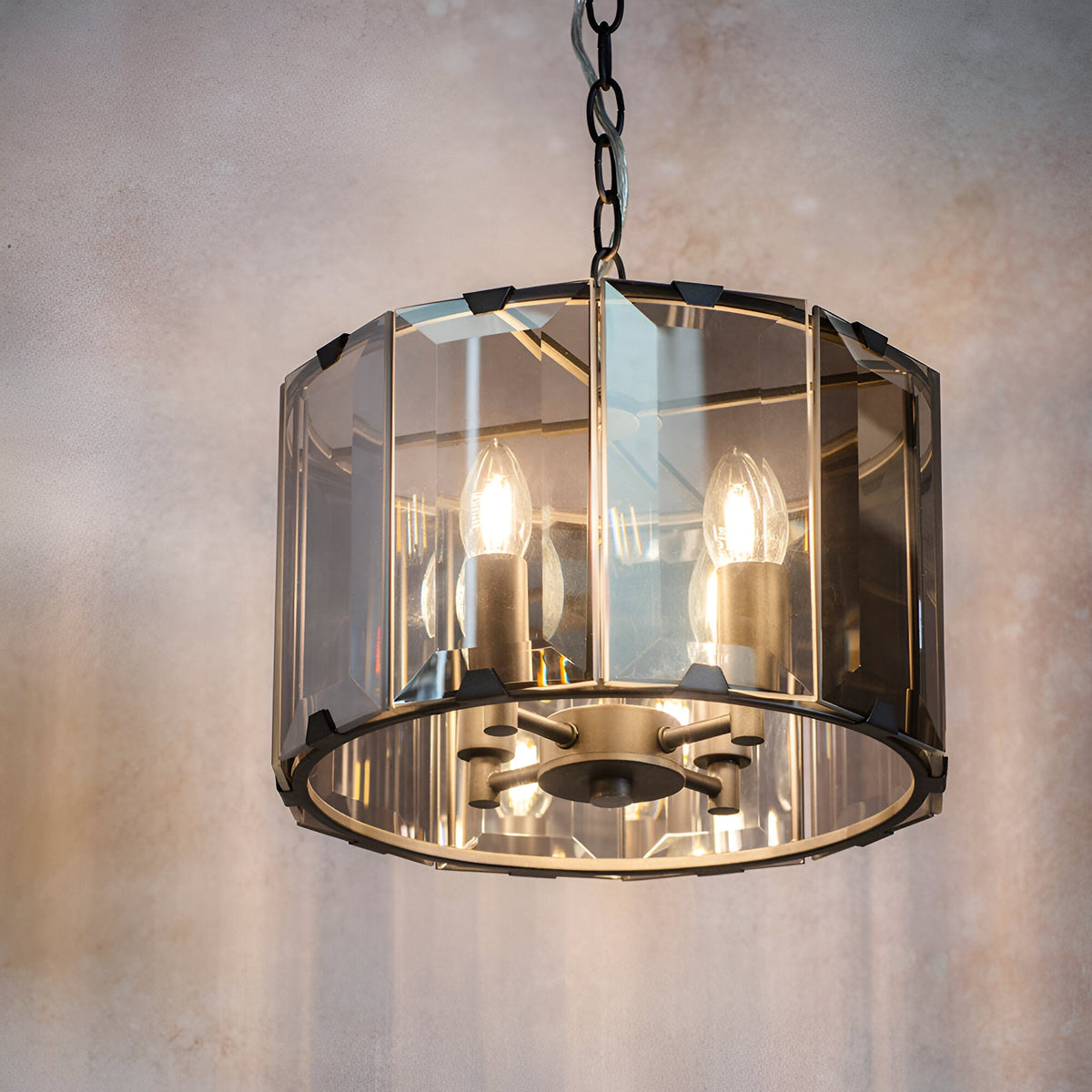 Bevshaw 4-light pendant in slate grey with a drum frame, bevelled smoke glass panels, exposed candle bulbs, and a chain hang.