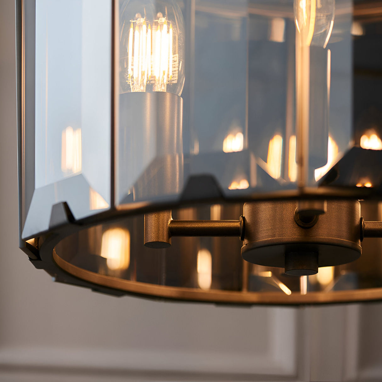 Bevshaw 4 Light Pendant close-up showing bevelled smoke glass panels, slate grey frame, and exposed filament bulbs with brass-toned fittings.