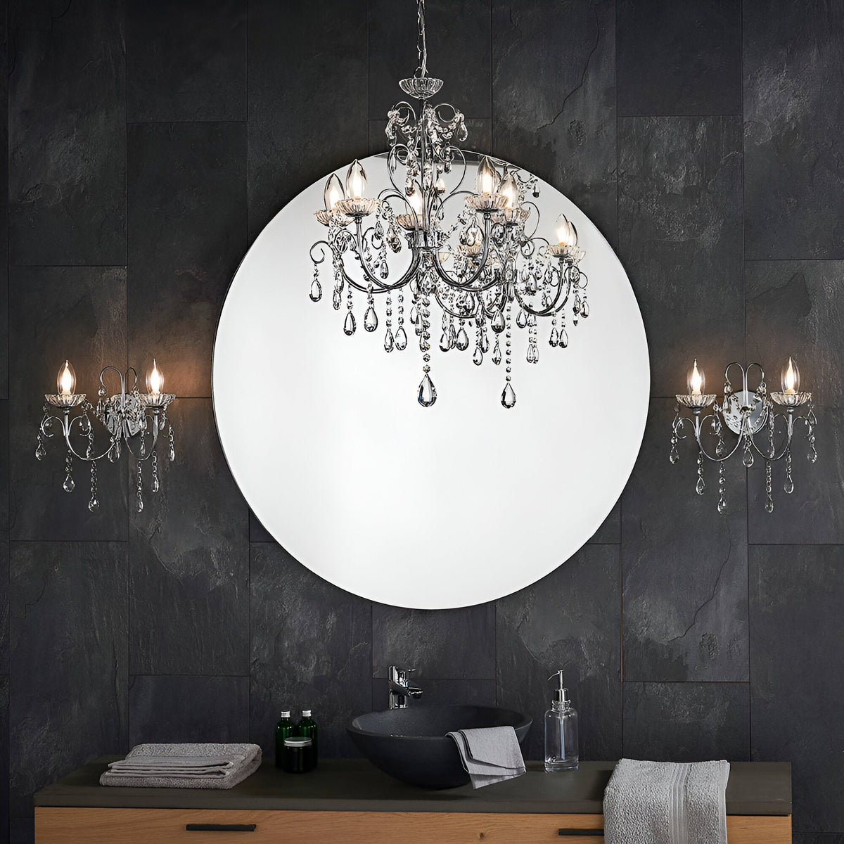 Endon Crandon 5 light bathroom chandelier in polished chrome with crystal droplets, reflected in a round mirror above a dark tiled vanity.