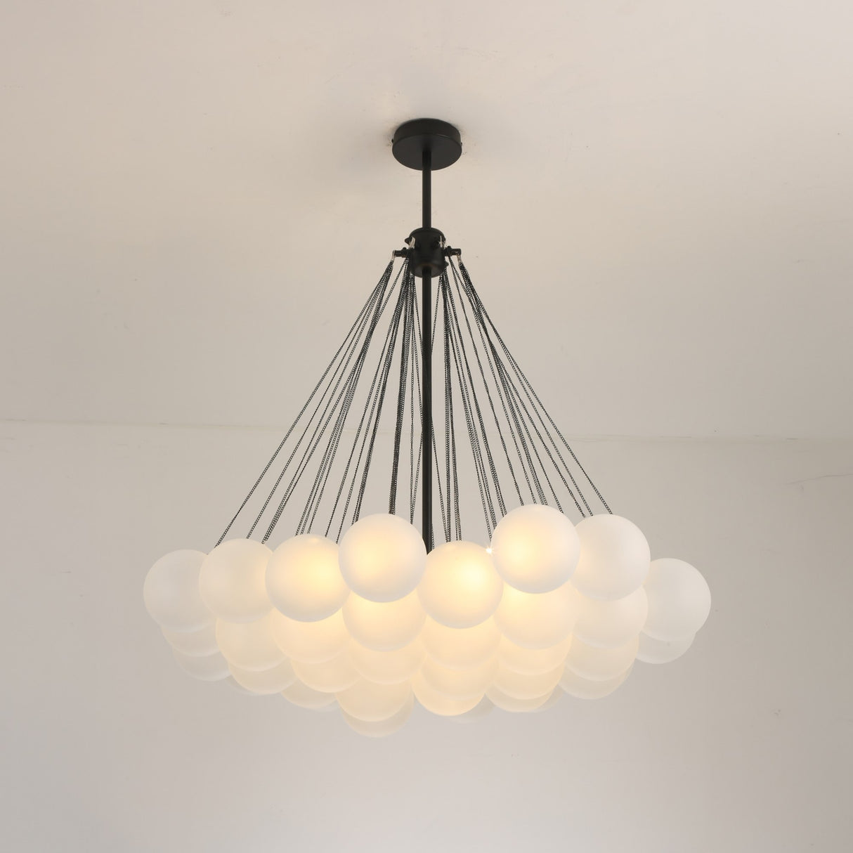 Niori Orb 37 Light Cluster Chandelier in black with frosted glass globes suspended on fine chains from a matt black ceiling rose and drop rod.