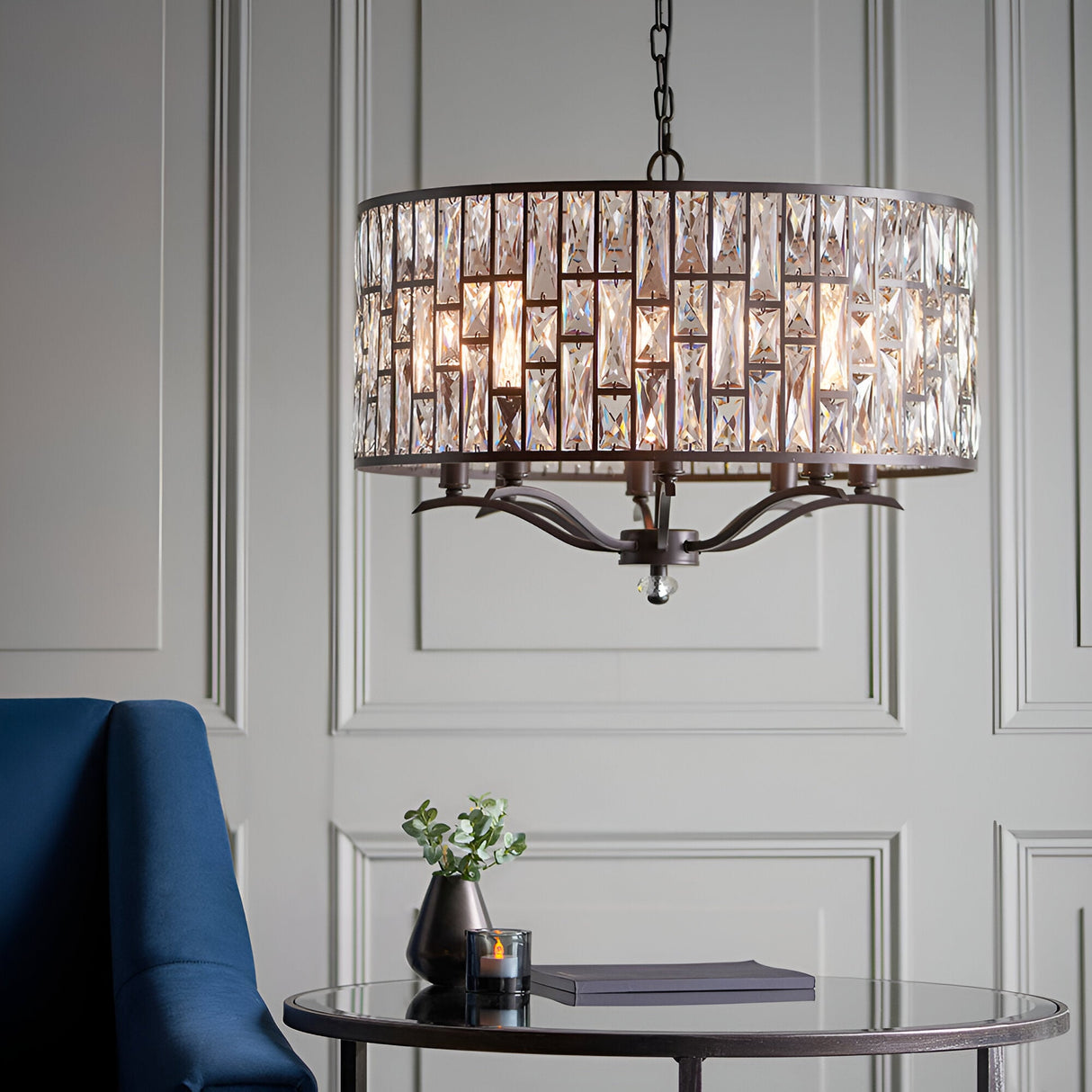Endon Aldwick 8 light pendant in dark bronze with tiered faceted crystal drum shade, hung above a mirrored side table in a panelled living room.