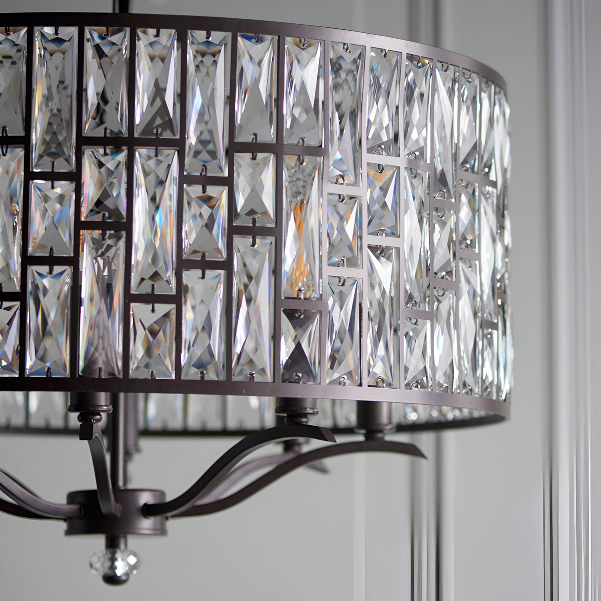 Close-up of Endon Aldwick 8 Light Pendant in dark bronze, showing tiered faceted K5 crystal drum shade and curved arms against a pale panelled wall.