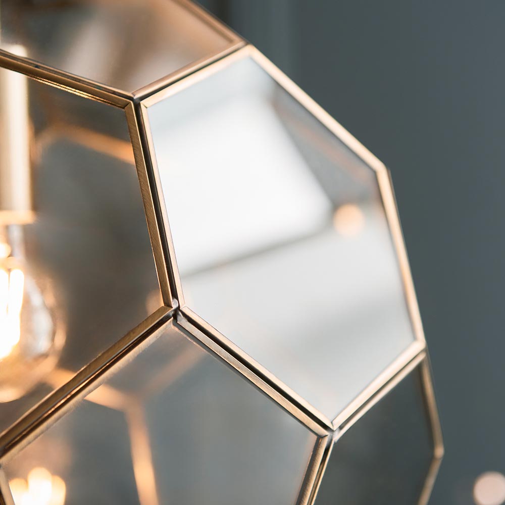 Close-up of the Endon Carldon Hexagonal Pendant showing clear glass panels edged in antique brass with a glowing E27 bulb visible within.