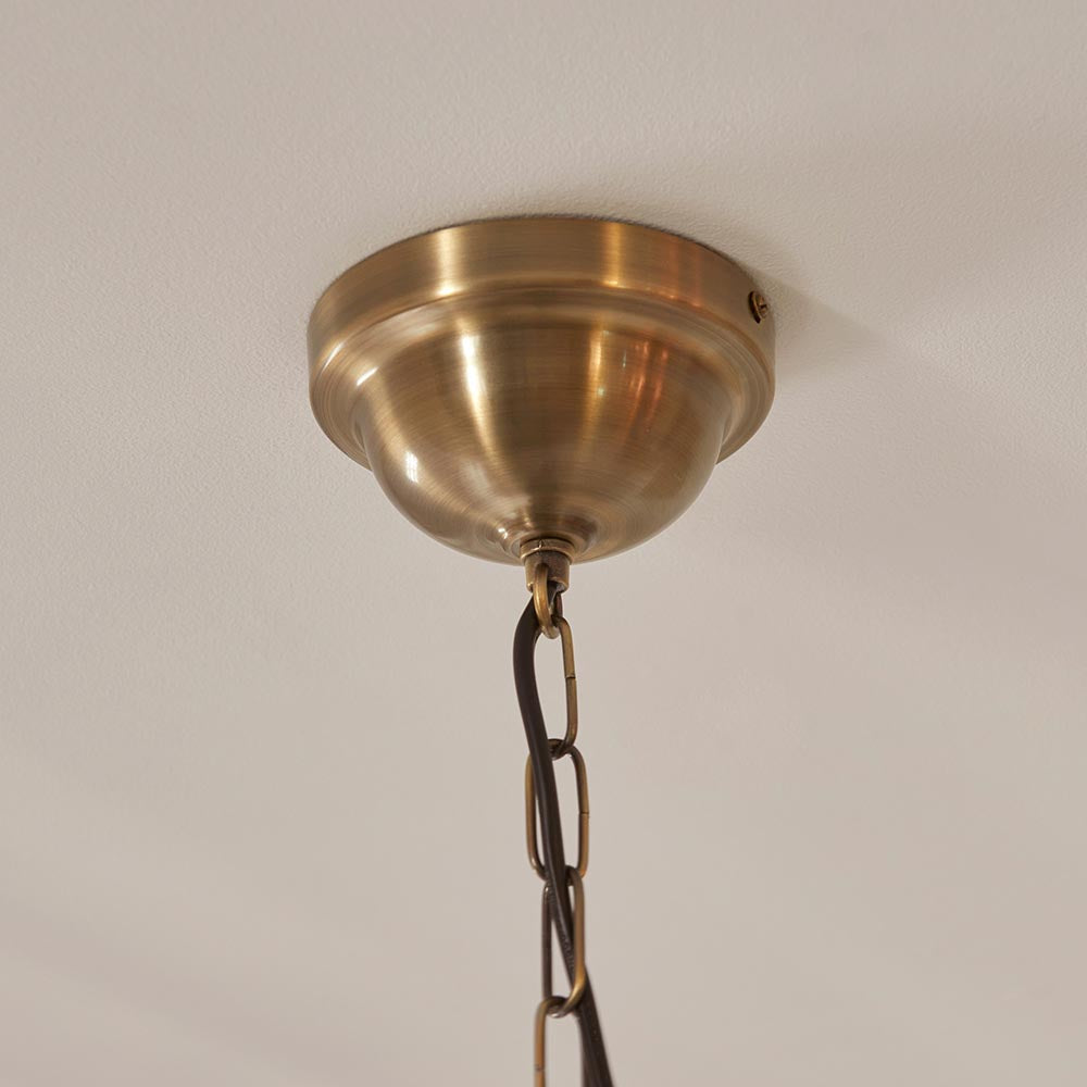 Close-up of the Endon Carldon pendant's antique brass ceiling rose and decorative chain fixed to a plain white ceiling.
