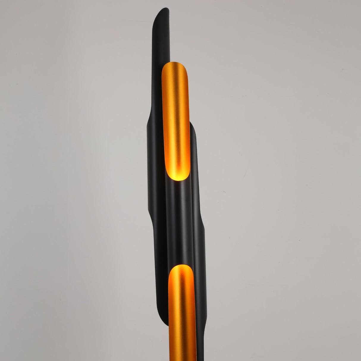 The Stealth 6 Light Floor Lamp in brass and black features a modern vertical design with curved, overlapping shapes. Cut-out sections emit a warm yellow-orange glow, making it perfect for adding stylish, contemporary lighting to any room.