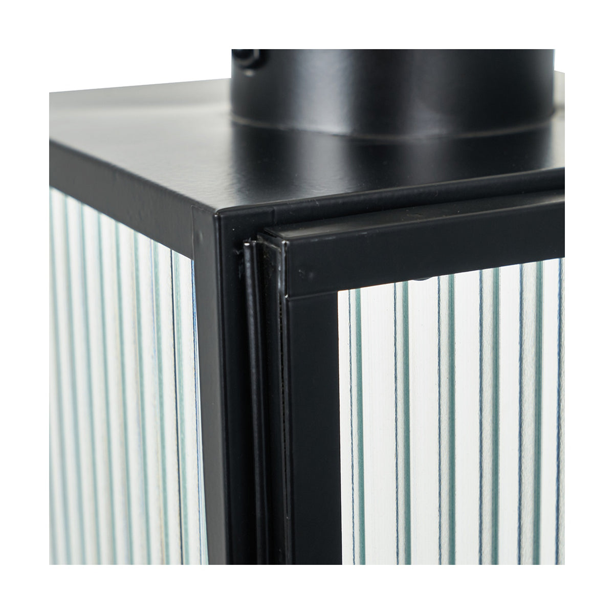 Close-up of a black iron candle lantern from the Set of 2 Black Iron & Ribbed Glass Lanterns, showing the corner frame joinery and ribbed glass panel against a plain white background.