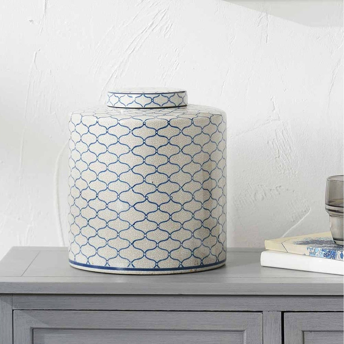 Demetri Grey & Blue Ceramic Lidded Ginger Jar, 24cm, with a quatrefoil pattern, shown on a grey sideboard beside books and a glass in a living room setting.