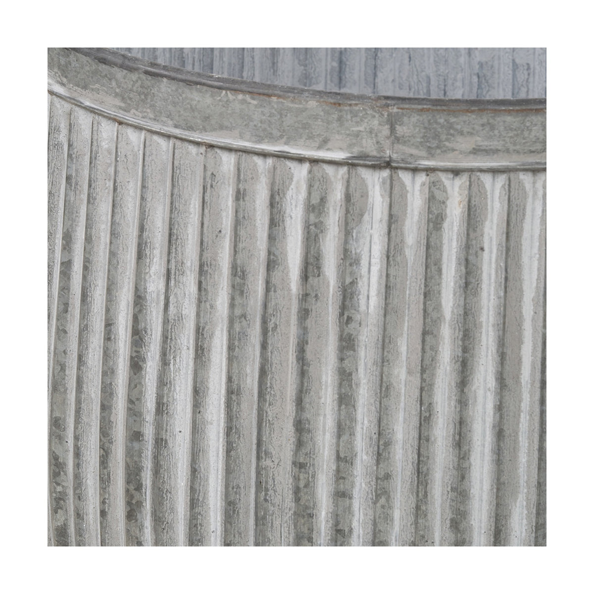 Close-up of a galvanised zinc barrel planter from a set of 2, showing vertical ribbed texture and a rolled rim seam in weathered grey metal.