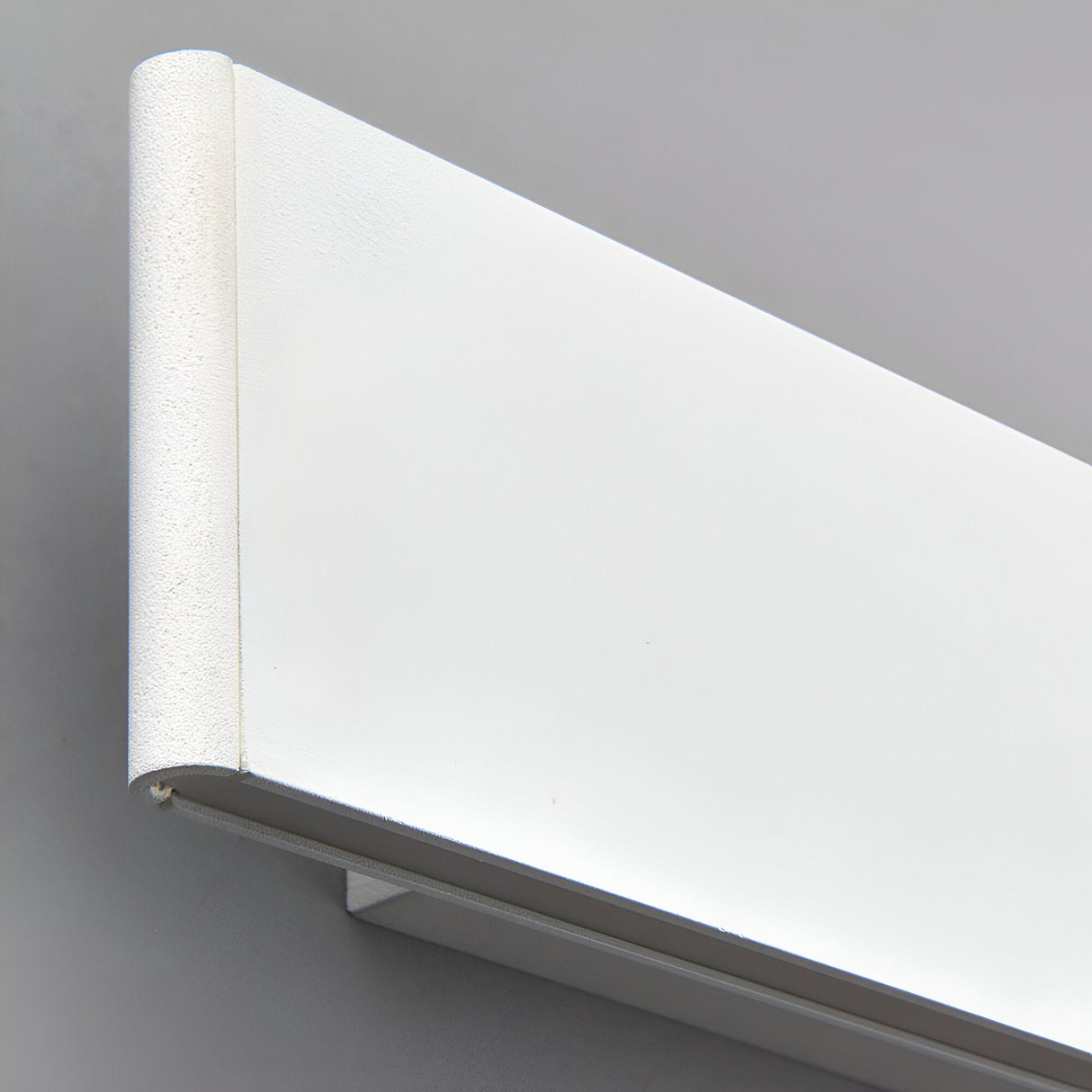 Close-up of the Endon Ambrose matt white LED wall light showing its slim rectangular form and curved end cap against a grey wall.