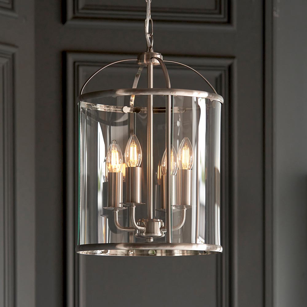 Endon Caldbury 4 Light Pendant in nickel with clear glass panels and four E14 candle lamps, hung from a chain against a dark panelled wall.