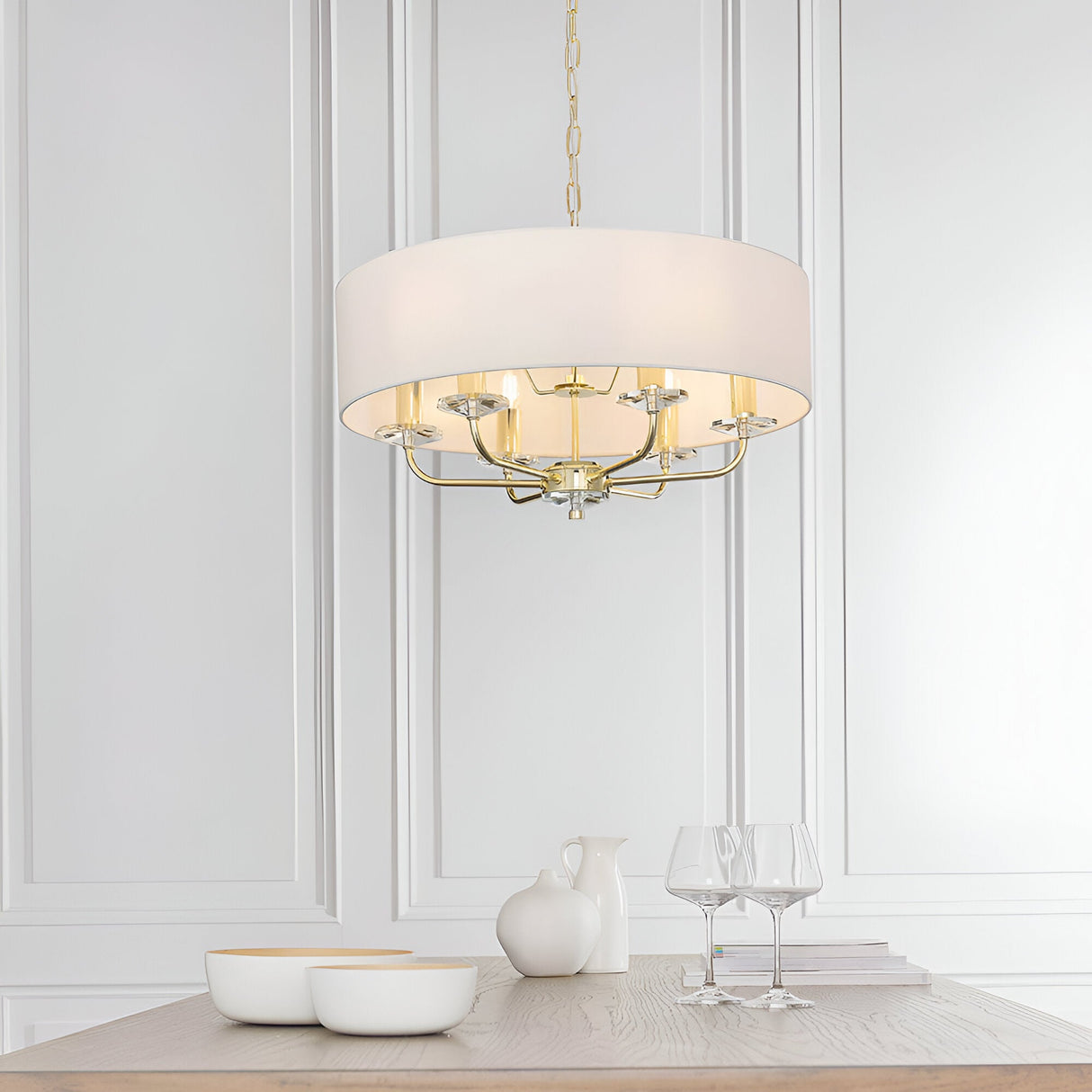 Endon Castdon 6 light pendant in brass with white faux silk drum shade and K9 crystal detail, hanging above a dining table in a panelled room.